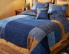 a bed in a bedroom with blue and brown quilts on the comforter next to a night stand