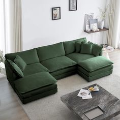 a living room with a large green couch and coffee table in front of the window