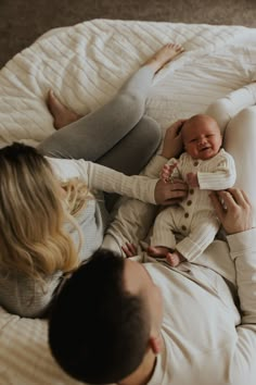 a man and woman laying on top of a bed holding a baby