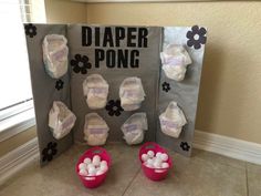 two buckets filled with white balls next to a diaper pong display