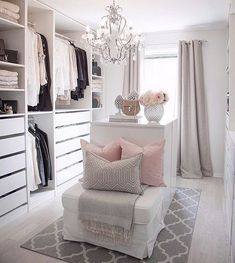 a white closet with chandelier, pillows and other items on the shelves in front of it