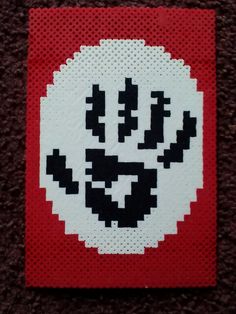 a red and white cross stitched coaster with a skull on it's face