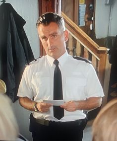 a man in uniform is holding papers and looking at the camera