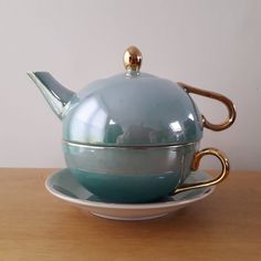 a tea pot and saucer sitting on top of a wooden table