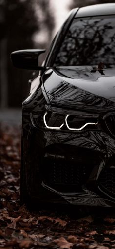 the front end of a black car with its lights on