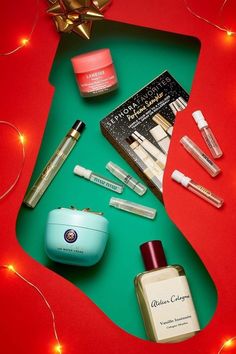 an assortment of beauty products on a green and red surface with christmas lights in the background