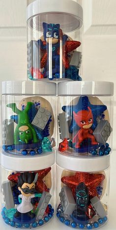 three plastic containers filled with cartoon figures on top of a table next to each other