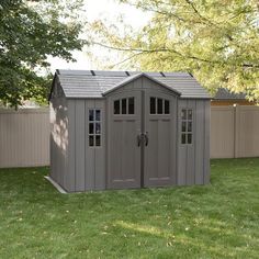 a gray shed sitting on top of a lush green field