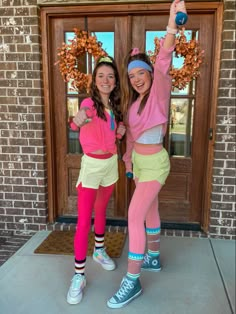 two girls are standing in front of a door and posing for the camera with their arms up