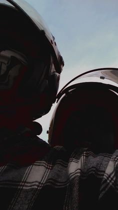 two people wearing helmets looking up into the sky