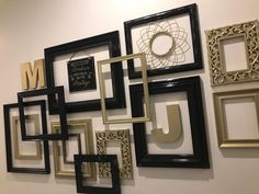 a wall with many different frames on it and the letters m in gold, black, and white