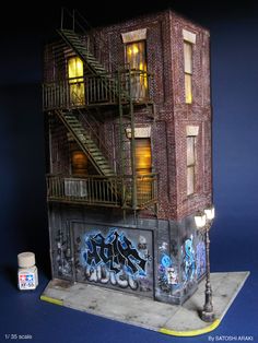 a model of a brick building with graffiti on the side and stairs up to it