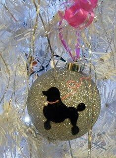 a black dog ornament hanging from a christmas tree with pink and white ornaments