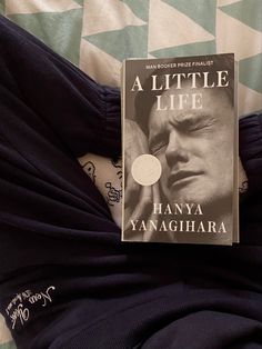 a book sitting on top of a bed next to a blue and white blanket with an image of a man's face