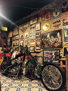 a motorcycle parked in front of a brick wall with posters on the wall behind it