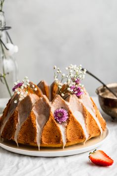 a bundt cake with white icing and flowers on top, sitting on a plate