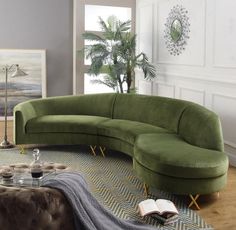 a large green couch sitting on top of a rug in a living room next to a window