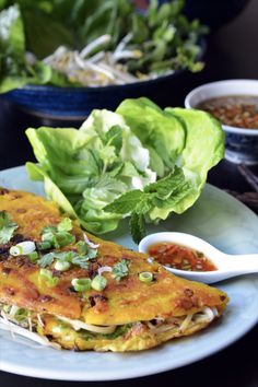 an omelet with lettuce and sauce on a plate next to salad