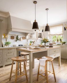 a large kitchen with two stools in front of the island and an open floor plan