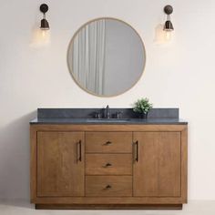 a bathroom vanity with a round mirror above it and two lights on the wall next to it