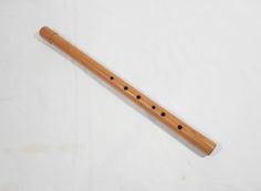 a wooden flute with black dots on the top and bottom, sitting on a white surface