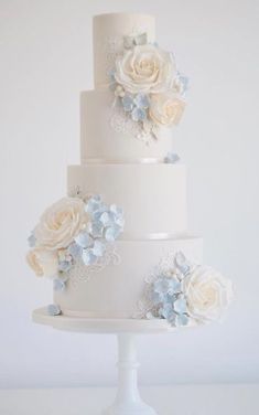 a white wedding cake with blue flowers on top