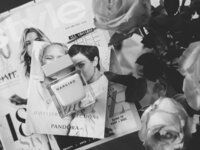 black and white photograph of two women in front of magazines with roses on the table