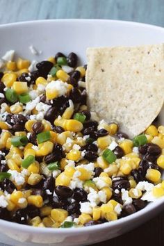 a white bowl filled with black beans, corn and cheese next to a tortilla