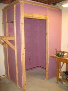 an unfinished room with pink walls and wood framing