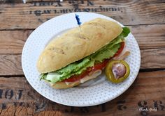 a sandwich with lettuce, tomato and cheese on a plate next to a pickle