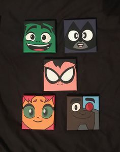 four square magnets with different cartoon faces on black paper and one has green eyes, the other is red