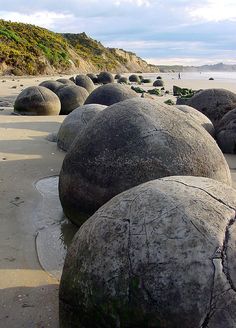 several large rocks sitting on top of a sandy beach