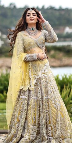 a woman in a yellow and white lehenga, with her hands on her head