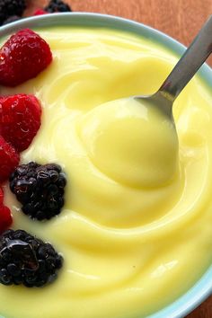 a bowl filled with yogurt and berries next to a spoon on a table