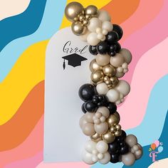 a graduation balloon garland with black, white and gold balloons