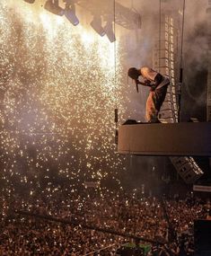 a man standing on top of a stage in front of a crowd at a concert