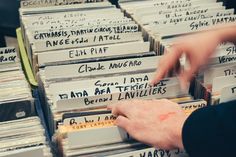 a person is picking up some records from a table full of other record players and their names on them