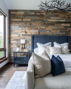 a large bed with pillows on it in a bedroom next to a wall made out of wood planks