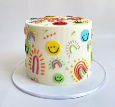 a white cake decorated with smiley faces and rainbows