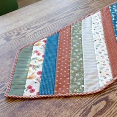 a wooden table topped with lots of different colored fabrics