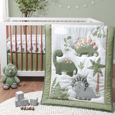 a baby crib bedding set with dinosaurs and trees on it, next to a teddy bear