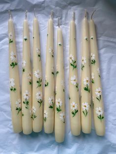 five candles with daisies painted on them