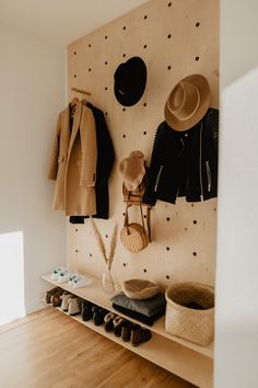 a coat rack with hats and coats hanging on it's sides, along with shoes