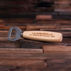 a bottle opener sitting on top of a wooden table next to a corkscrew