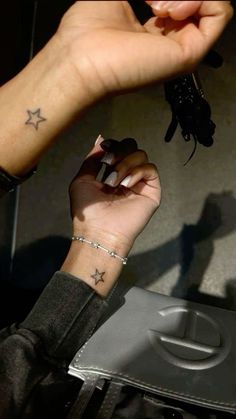 a woman's hand with a star tattoo on her left wrist holding a cell phone