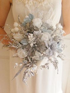 a bridal holding a silver and white bouquet in her hands with snowflakes on it