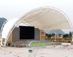 an outdoor stage is set up in the middle of a construction area with mountains in the background