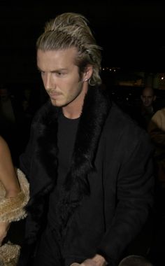 a man and woman are walking together at an event in the dark, one is wearing a fur collar