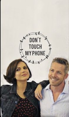 two people standing next to each other in front of a sign that says don't touch my phone