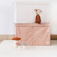 a stuffed animal sitting on top of a pink storage box next to mushrooms and mushrooms